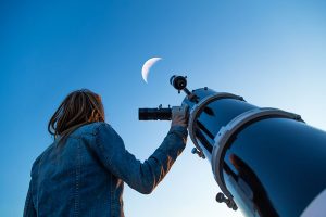 girl looking at the moon through lens